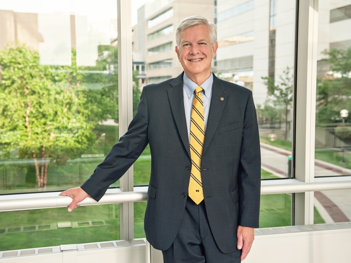 Marschall S. Runge, M.D., Ph.D., poses in a blue suit and yellow tie on the Michigan Medicine campus.