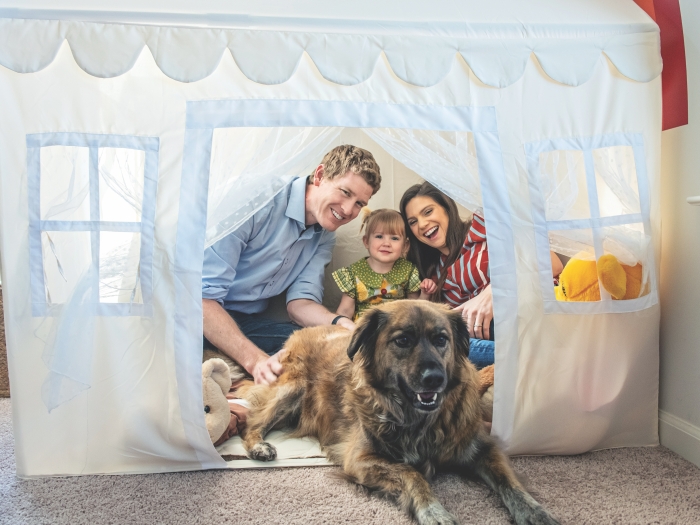 A family photo of Jake Ruduck with his wife, daughter, and dog. They are all sitting inside a white playhouse tent.