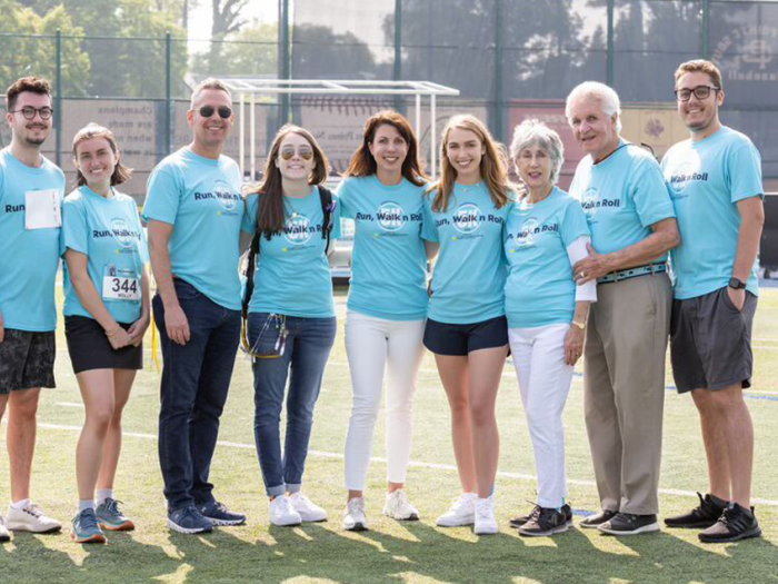 Sheeren Family wearing blue Run, Walk N Roll 5K t-shirts standing on football field.